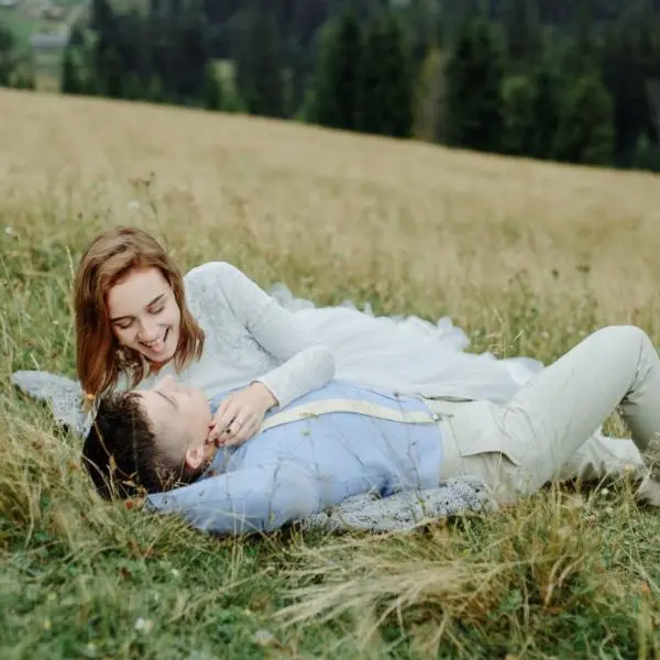Novios abrazados tumbados en el pasto durante una sesión de fotos romántica de boda en Mallorca.