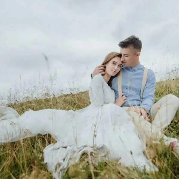 Pareja de novios sentados en el campo tras su boda en Mallorca, momento íntimo y natural.